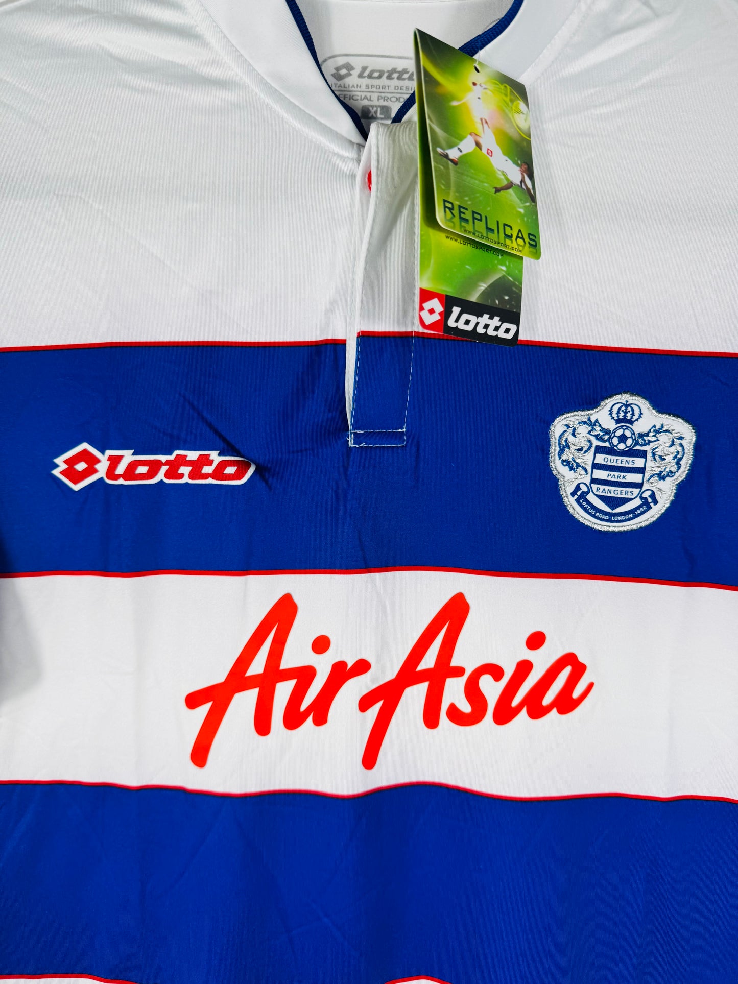 Gros plan sur l'écusson de QPR, le logo Lotto rouge et le sponsor AirAsia.