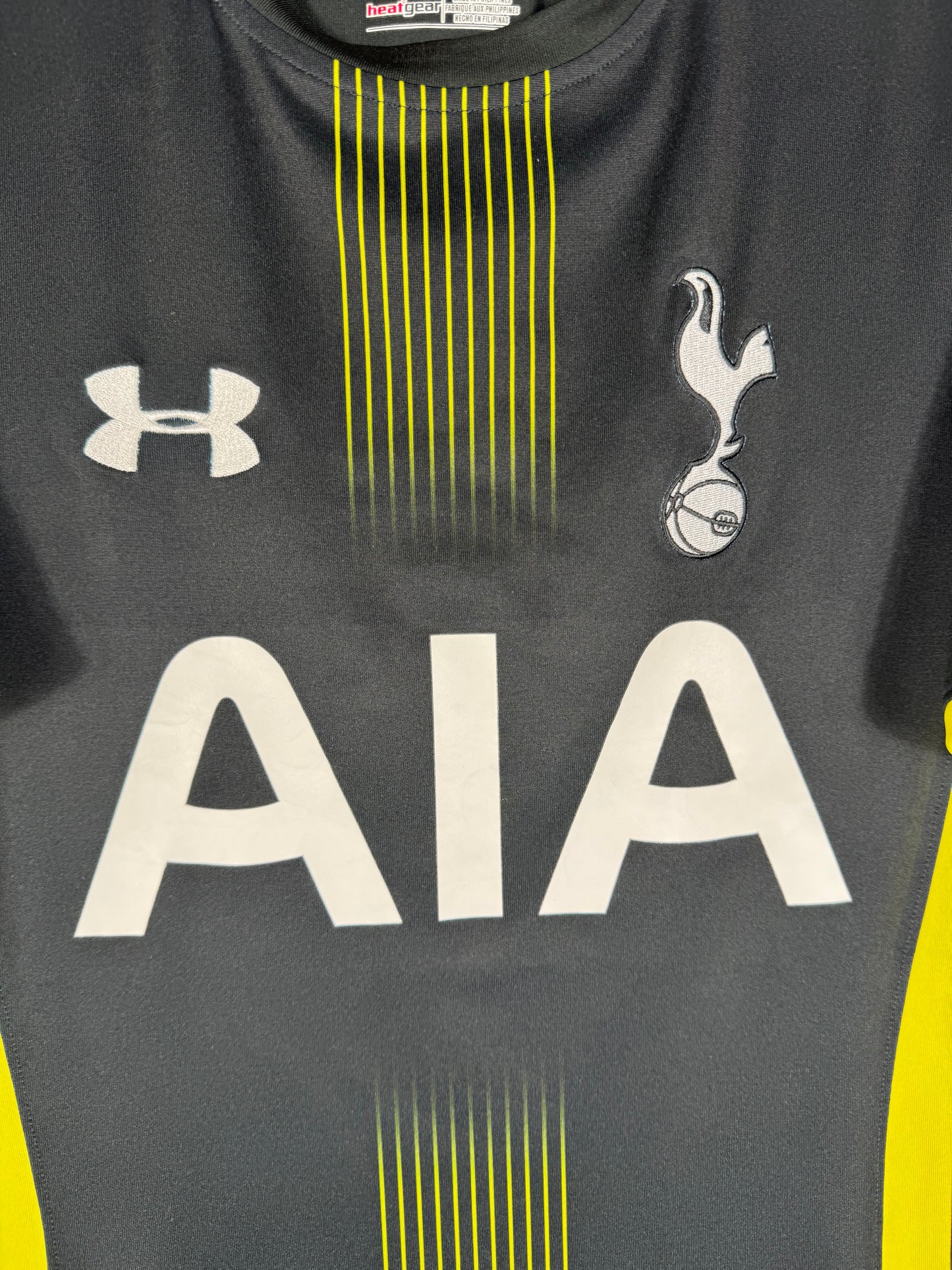 Gros plan sur l'écusson de Tottenham Hotspur et le logo Under Armour sur le torse.