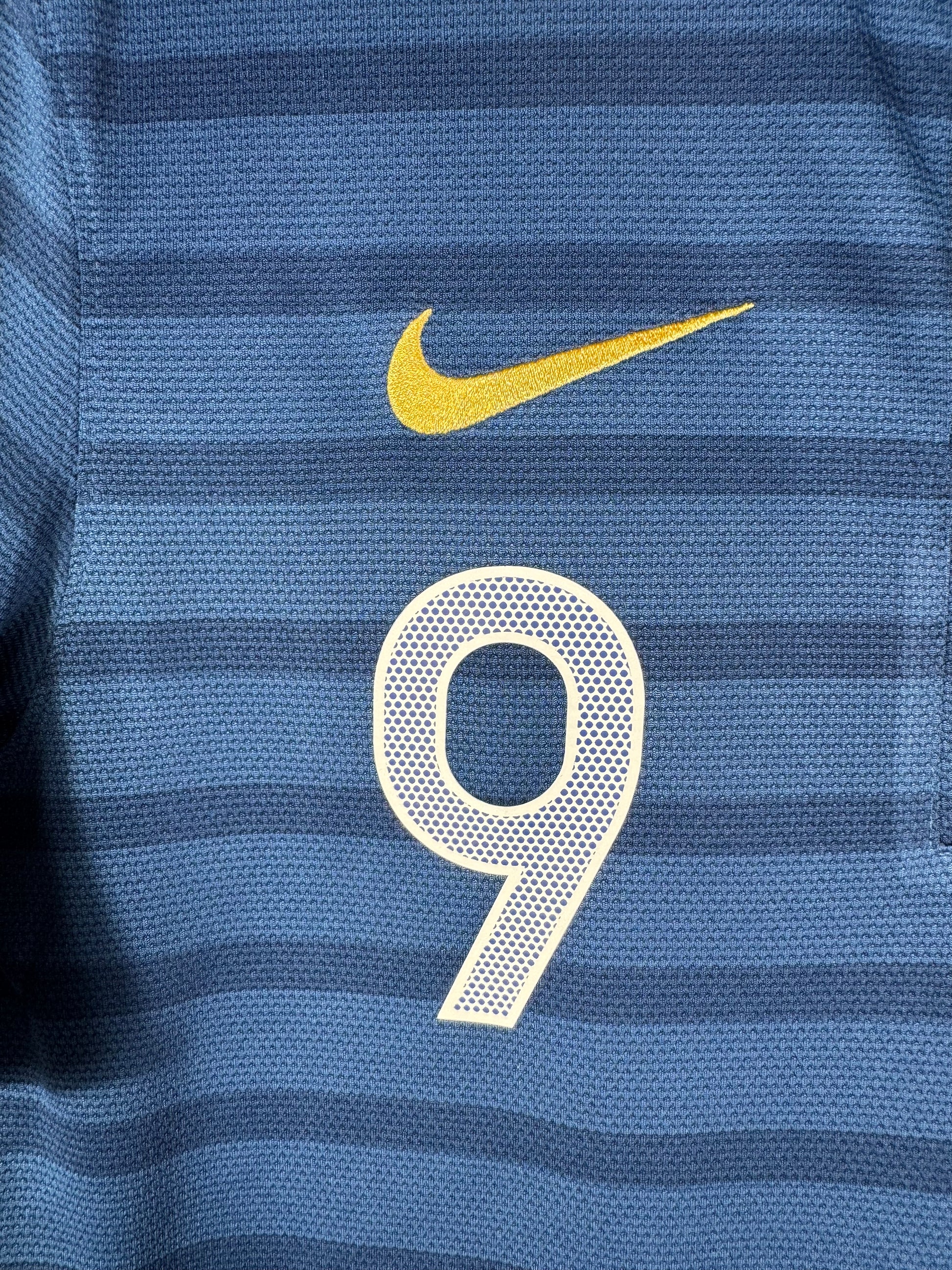 Gros plan sur le logo Nike doré et le numéro 9 sur le torse du maillot français.