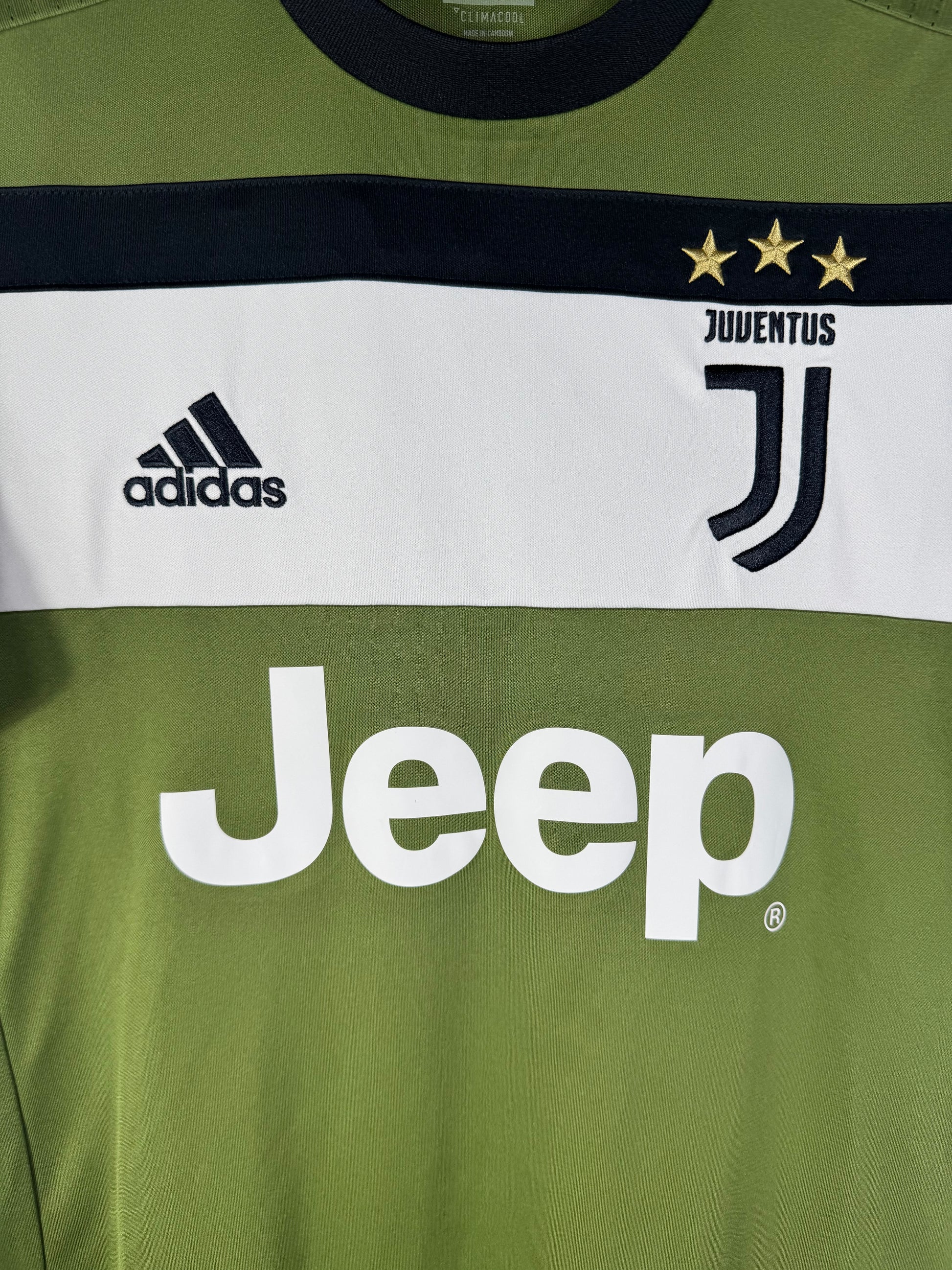 Gros plan sur le nouveau logo J de la Juventus, les 3 étoiles d'or et le sponsor Jeep sur le maillot vert.