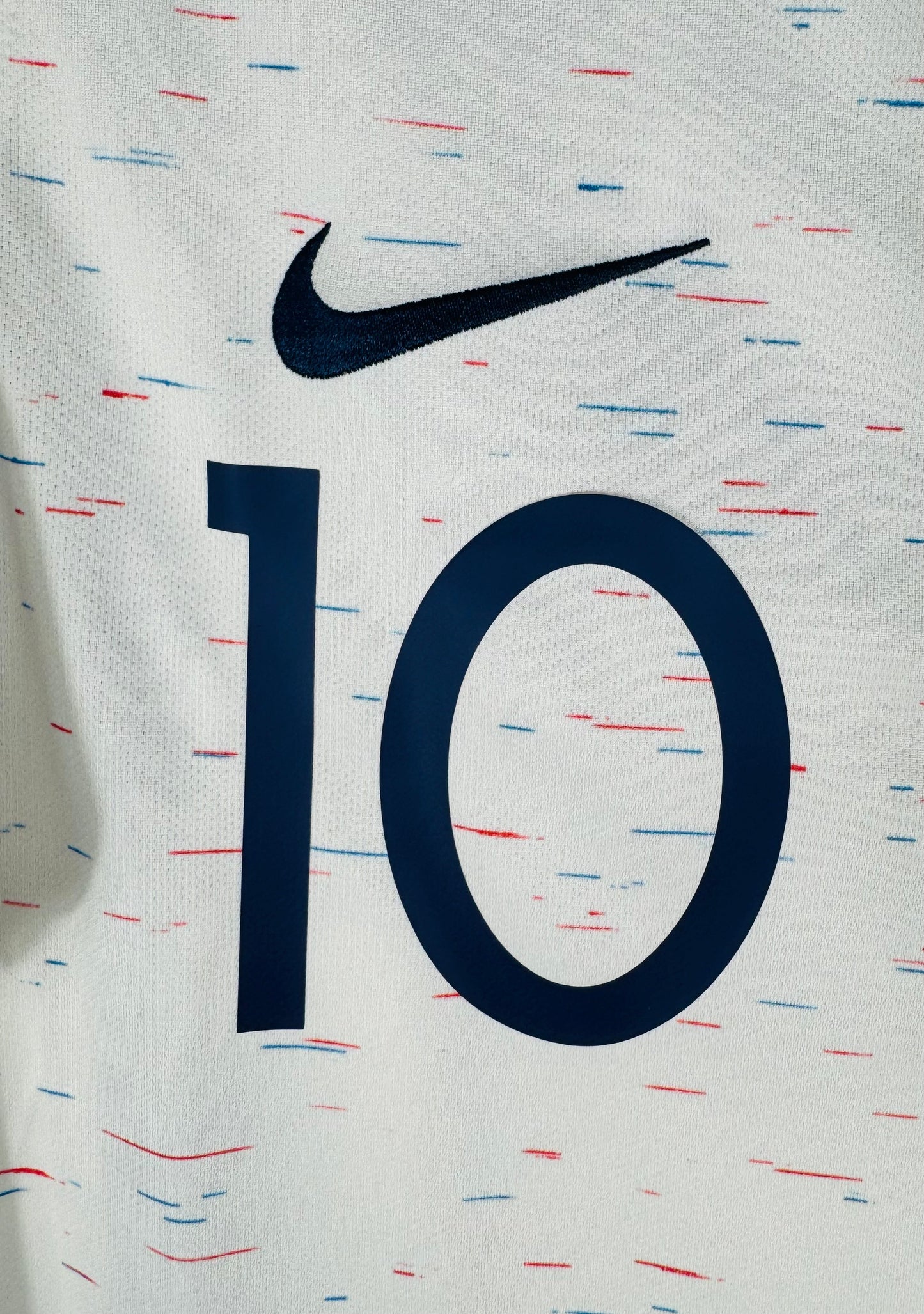 Gros plan sur le numéro 10 bleu marine et le Swoosh Nike sur le tissu texturé.