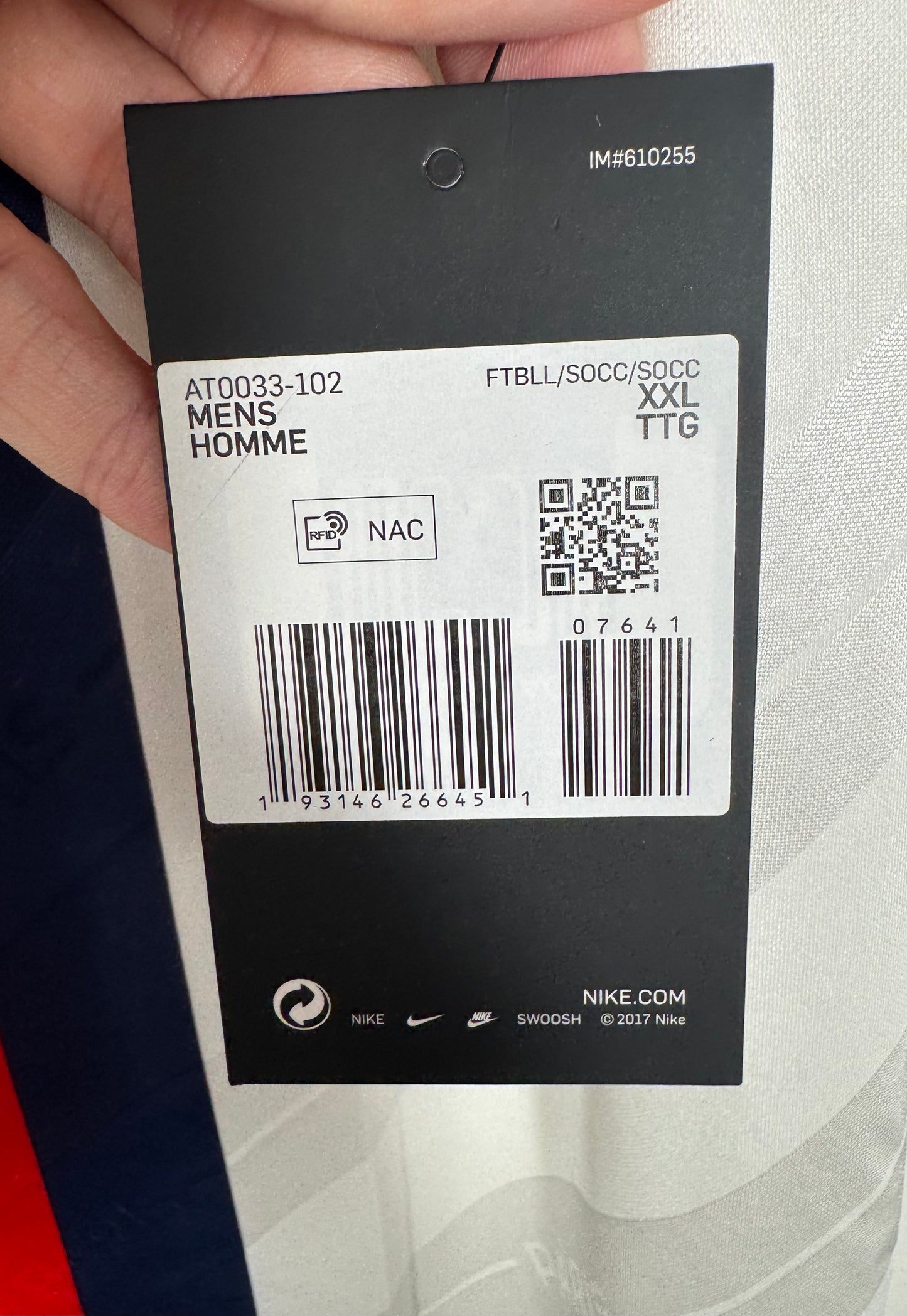Gros plan sur les étiquettes cartonées Nike attachées au maillot, preuve de l'état neuf.