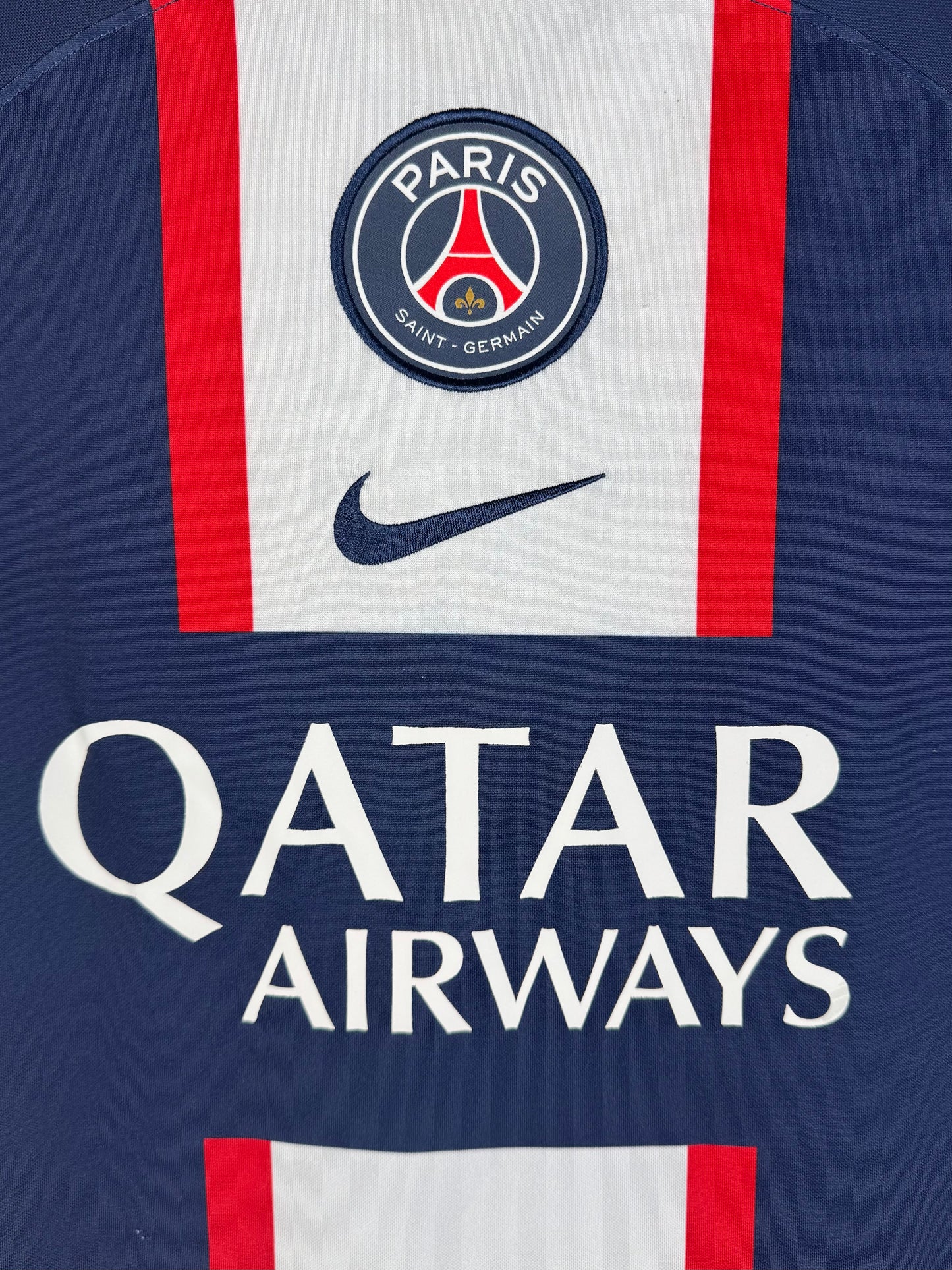 Détail écusson Paris Saint-Germain et sponsor Qatar Airways sur maillot domicile.