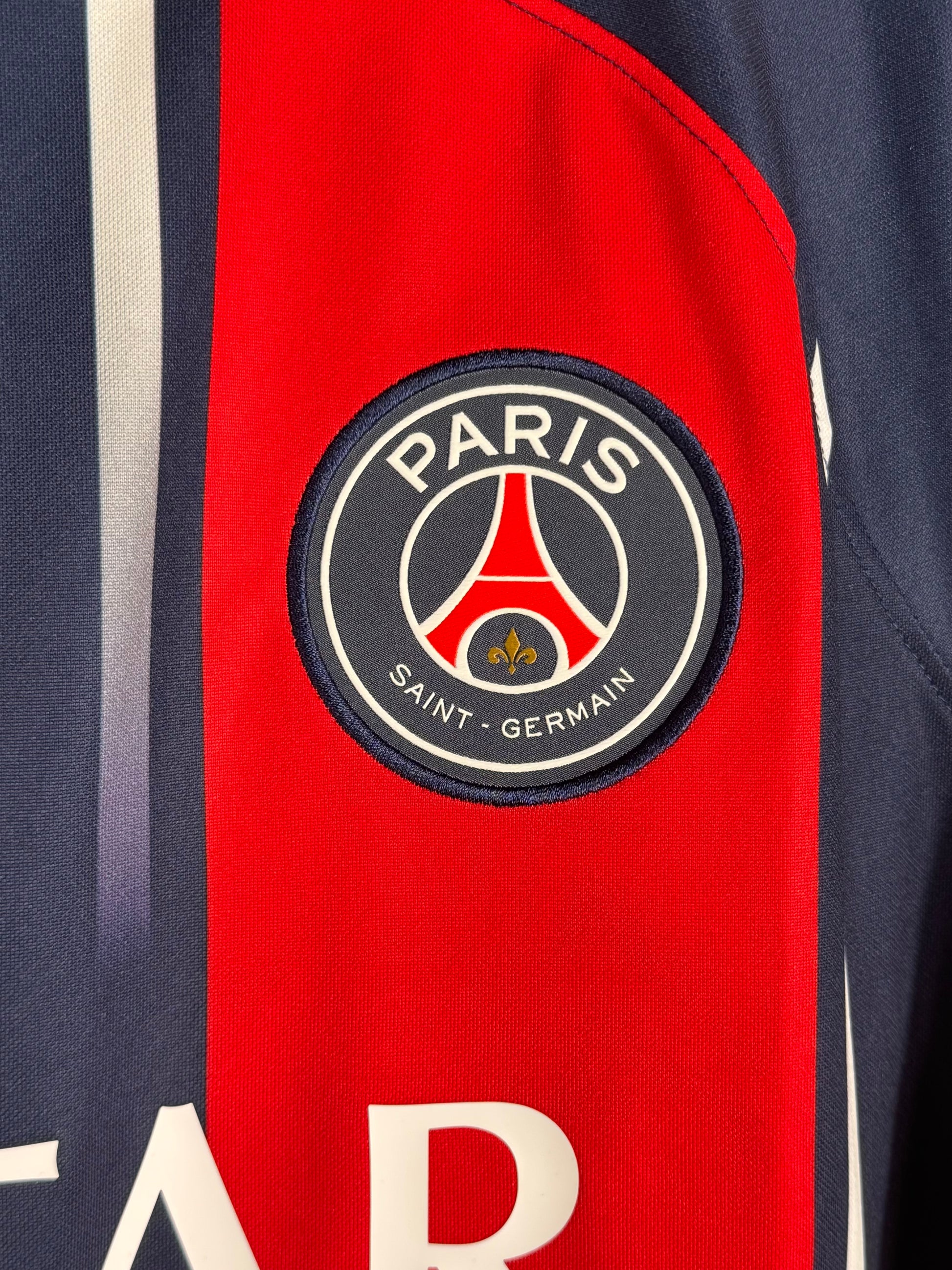 Détail écusson Paris Saint-Germain et texture bande rouge fondue maillot domicile.