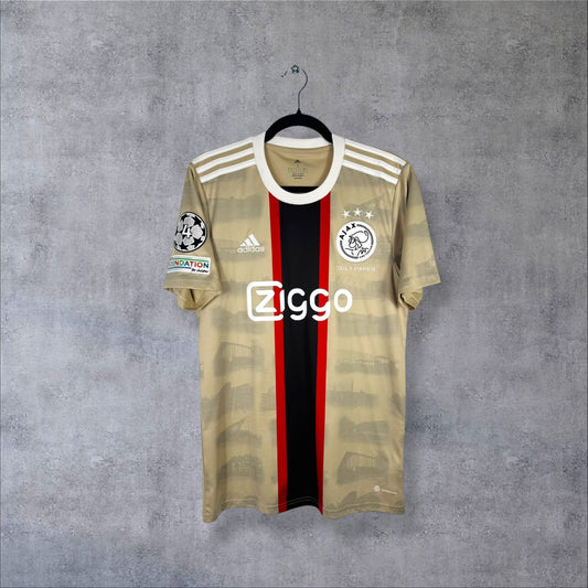 Maillot Ajax third 2022-2023 de face, bande noire et rouge, imprimé de tribunes et sponsor Ziggo