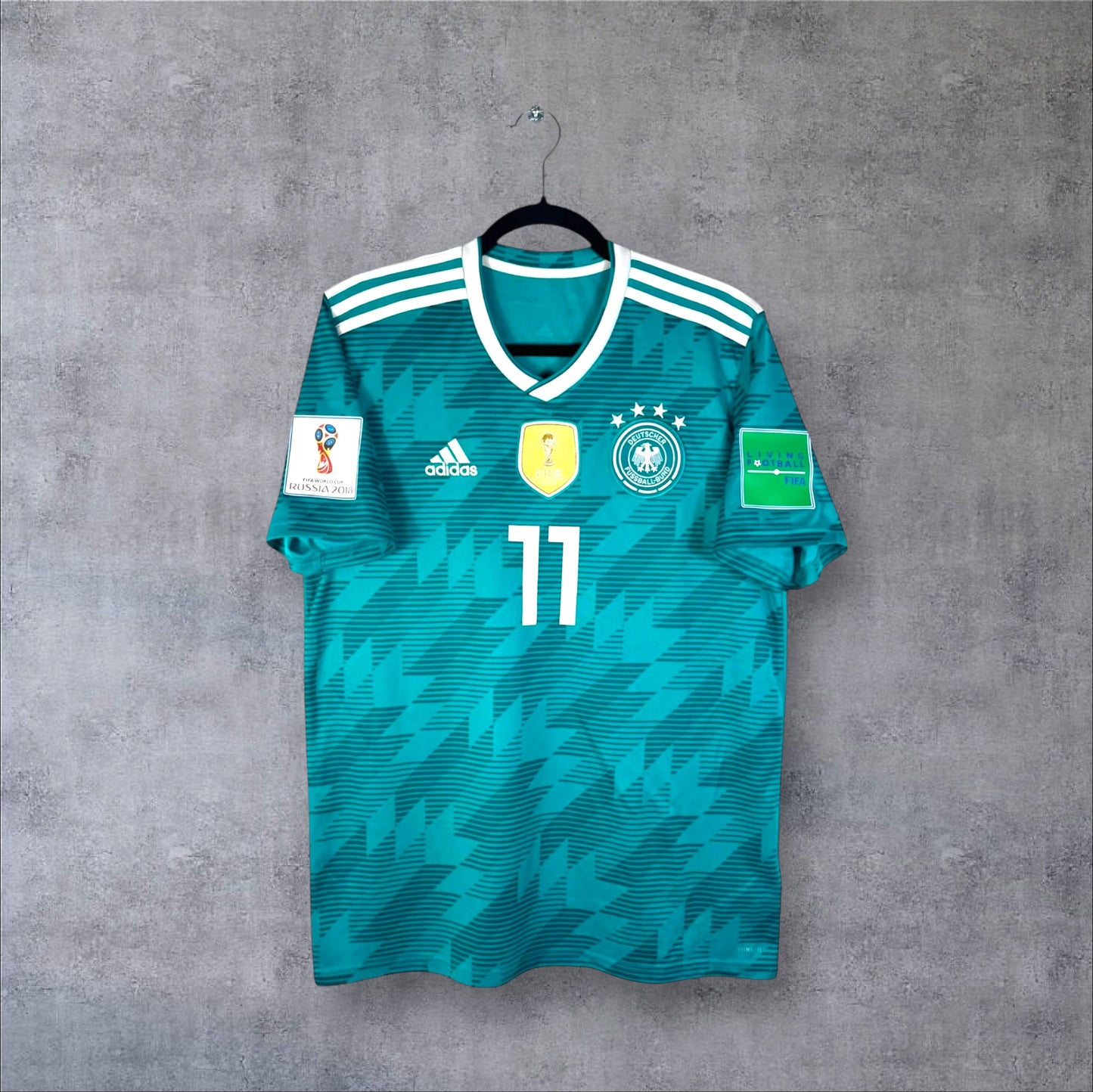 Vue de face du maillot Allemagne Extérieur 2018 vert avec badge de champion du monde doré, numéro 11 et col blanc.