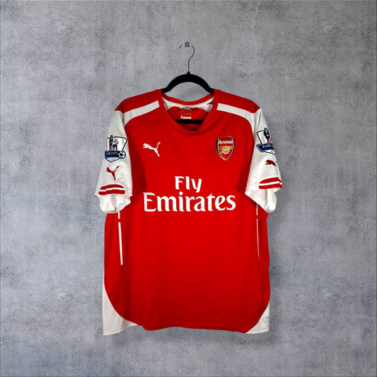 Face du maillot Arsenal 2014-2015 domicile Puma avec sponsor Fly Emirates, écusson des Gunners et manches blanches