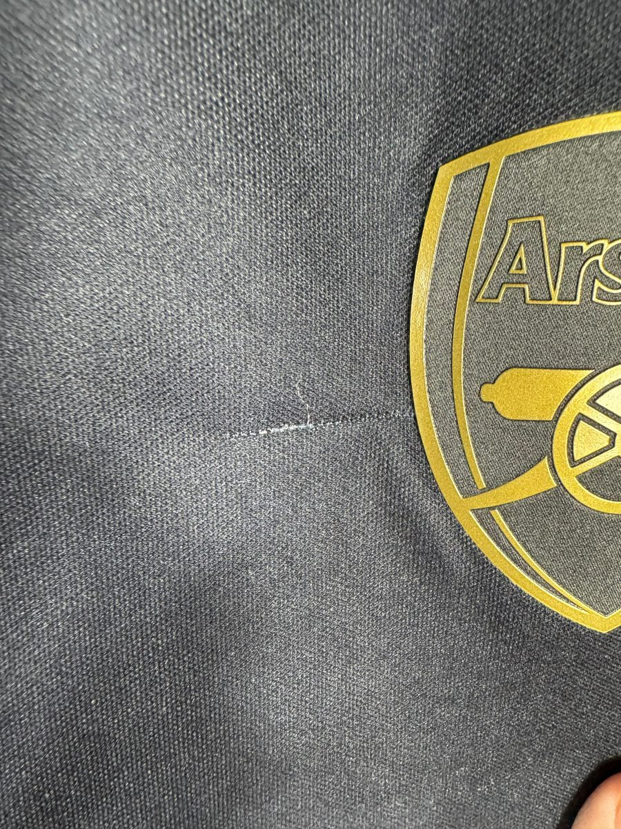 Défaut du maillot Arsenal 2015-2016 third : petit accroc dans la maille juste à côté de l'écusson doré