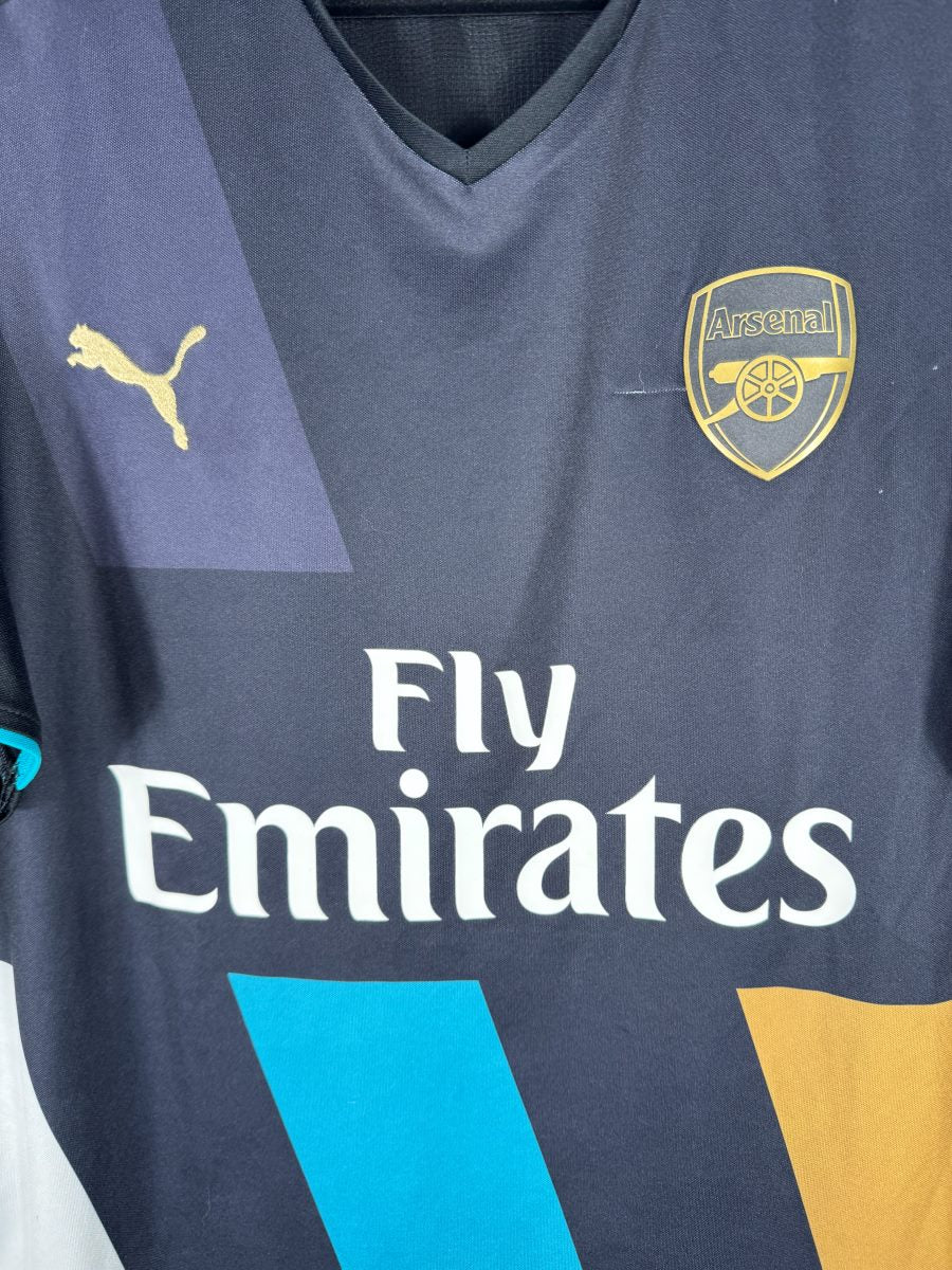 Détail de l'écusson doré d'Arsenal et du puma bond doré sur le maillot third 2015-2016 des Gunners