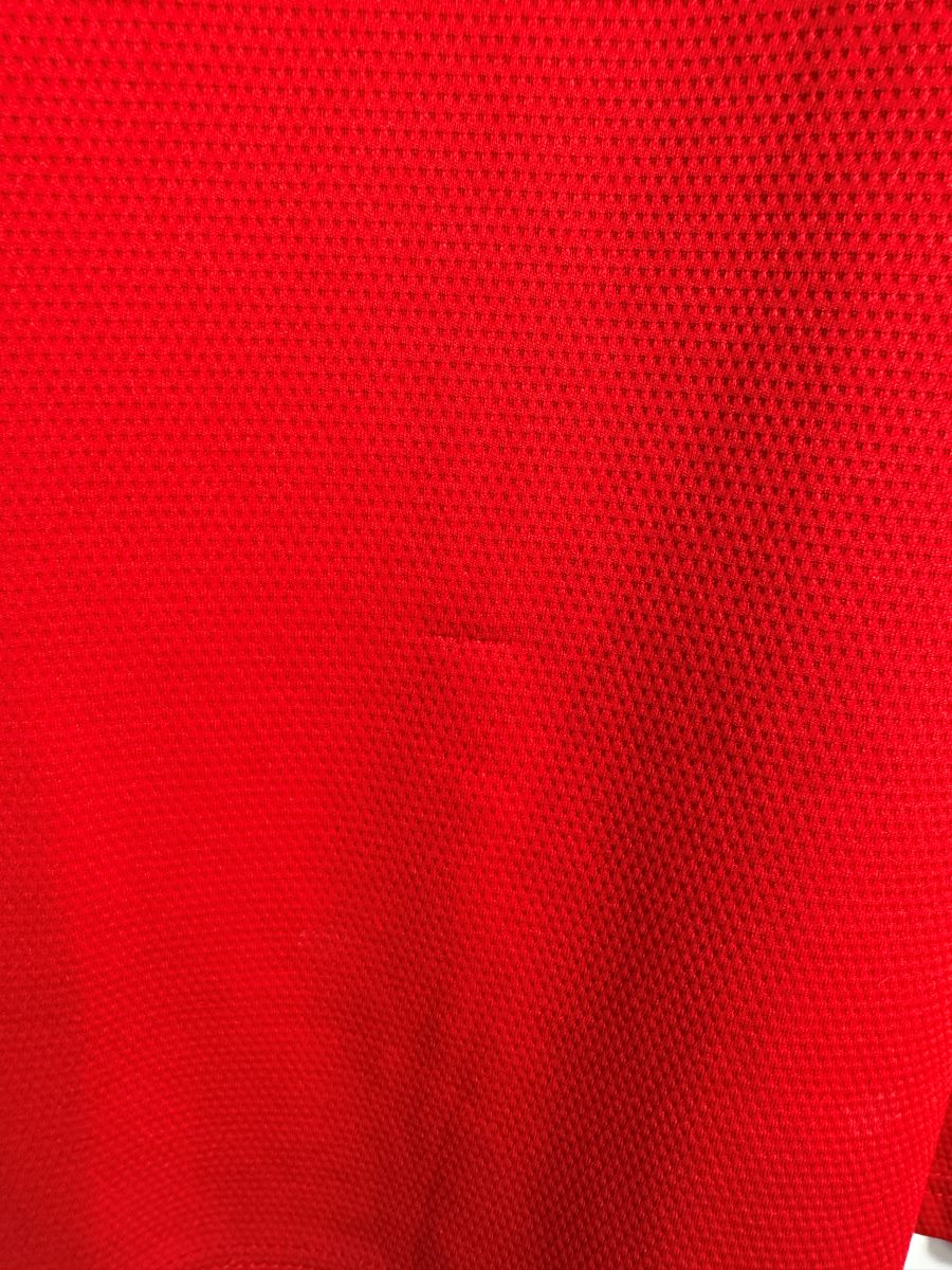 Micro-accroc à peine visible dans la maille rouge, maillot Arsenal domicile 2021-2022