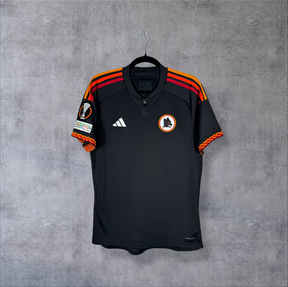 Face du maillot AS Roma 2023-2024 third adidas noir avec écusson lupetto rétro et manchettes tressées orange