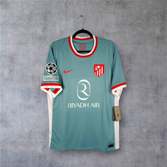 Vue de face du maillot Atletico Madrid Extérieur 2024/25 beige, sponsor Riyadh Air et logo historique.