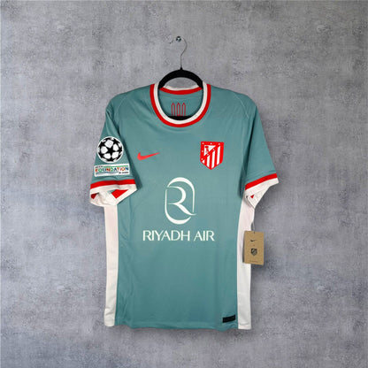 Vue de face du maillot Atletico Madrid Extérieur 2024/25 beige avec sponsor Riyadh Air.