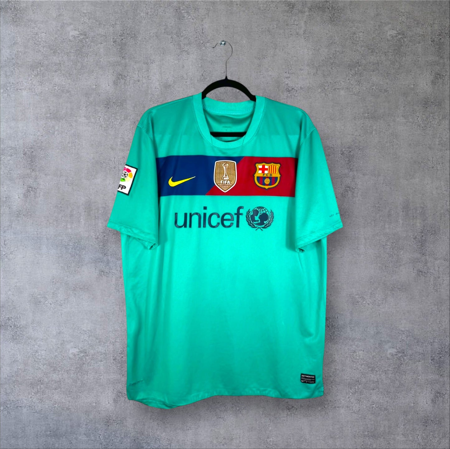 Vue de face du maillot FC Barcelone Extérieur 2010/11 vert avec bande blaugrana, sponsor Unicef et badge FIFA.