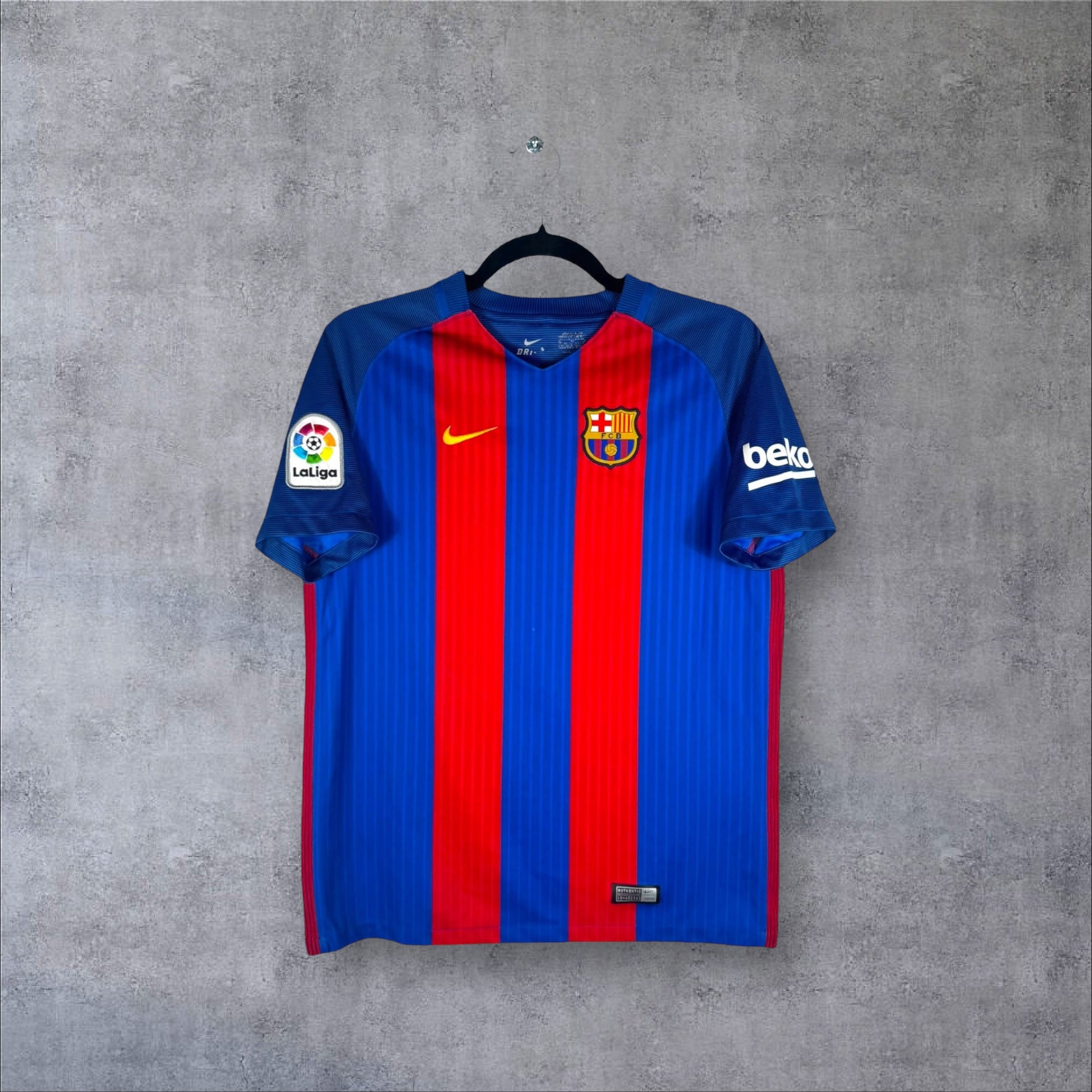 Vue de face du maillot FC Barcelone Domicile 2016/17 bleu et grenat à rayures classiques, col en V et sponsor Beko sur la manche.