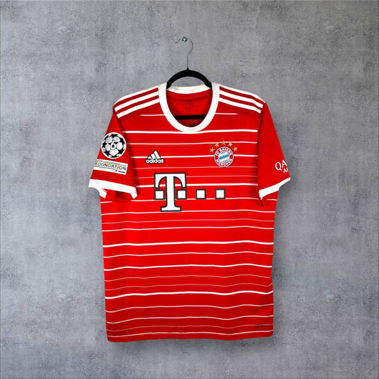 Vue de face du maillot Bayern Munich 2022/23 domicile rouge à rayures blanches avec sponsor Telekom.