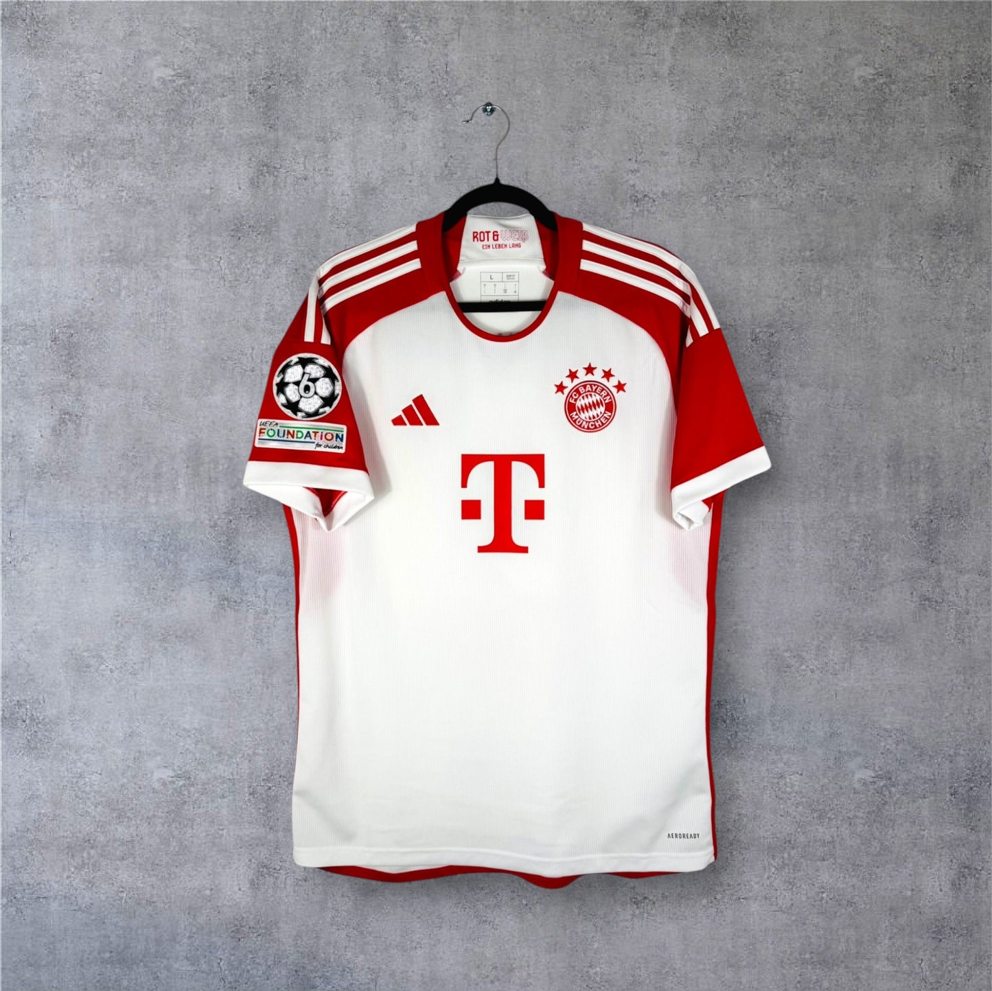 Vue de face du maillot Bayern Munich 2023/24 domicile blanc à manches rouges et sponsor T-Mobile.