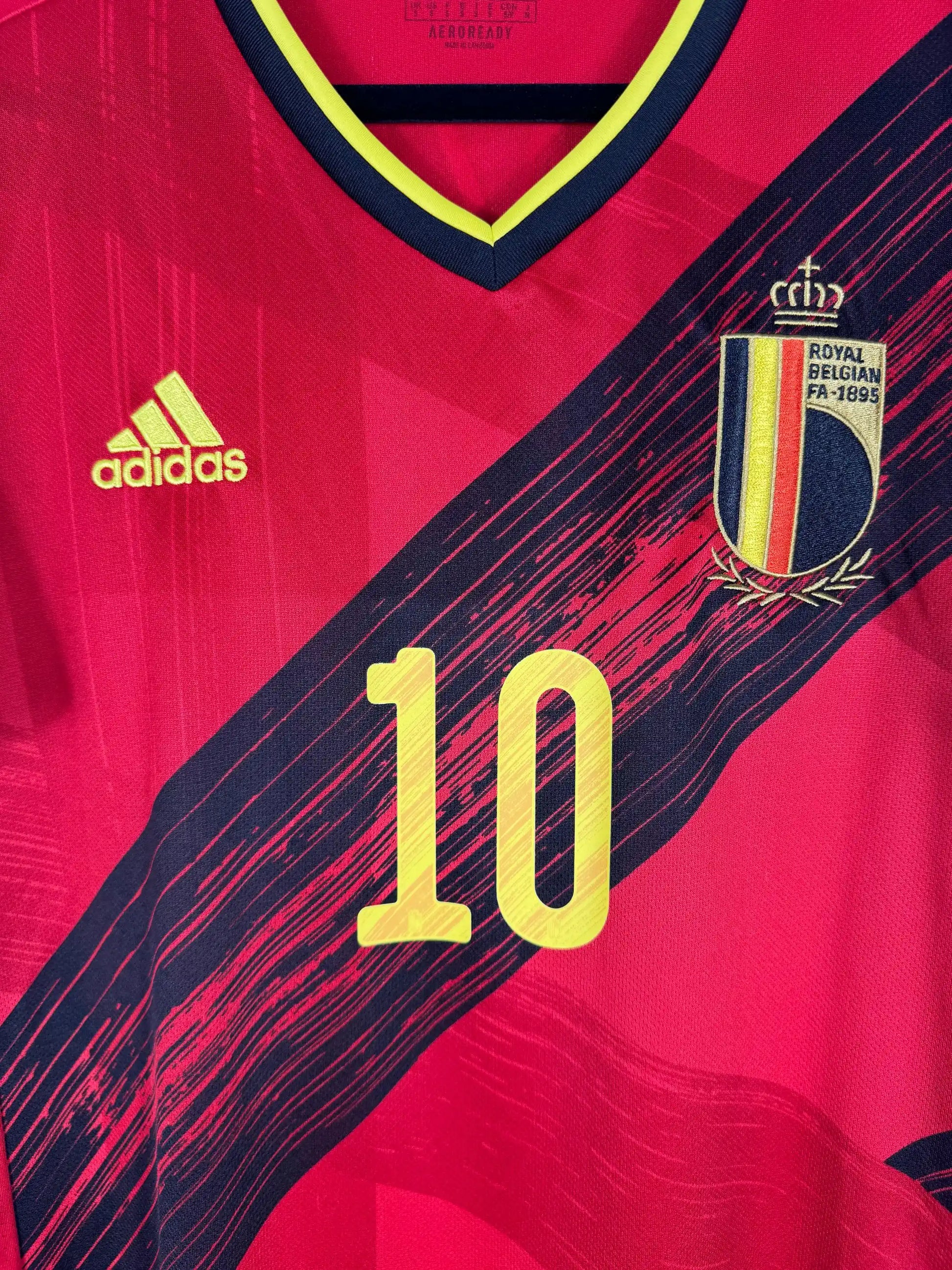 Détail écusson Royal Belgian Football Association et design diagonal tricolore belge jaune noir rouge sur maillot domicile Euro 2020 reporté COVID