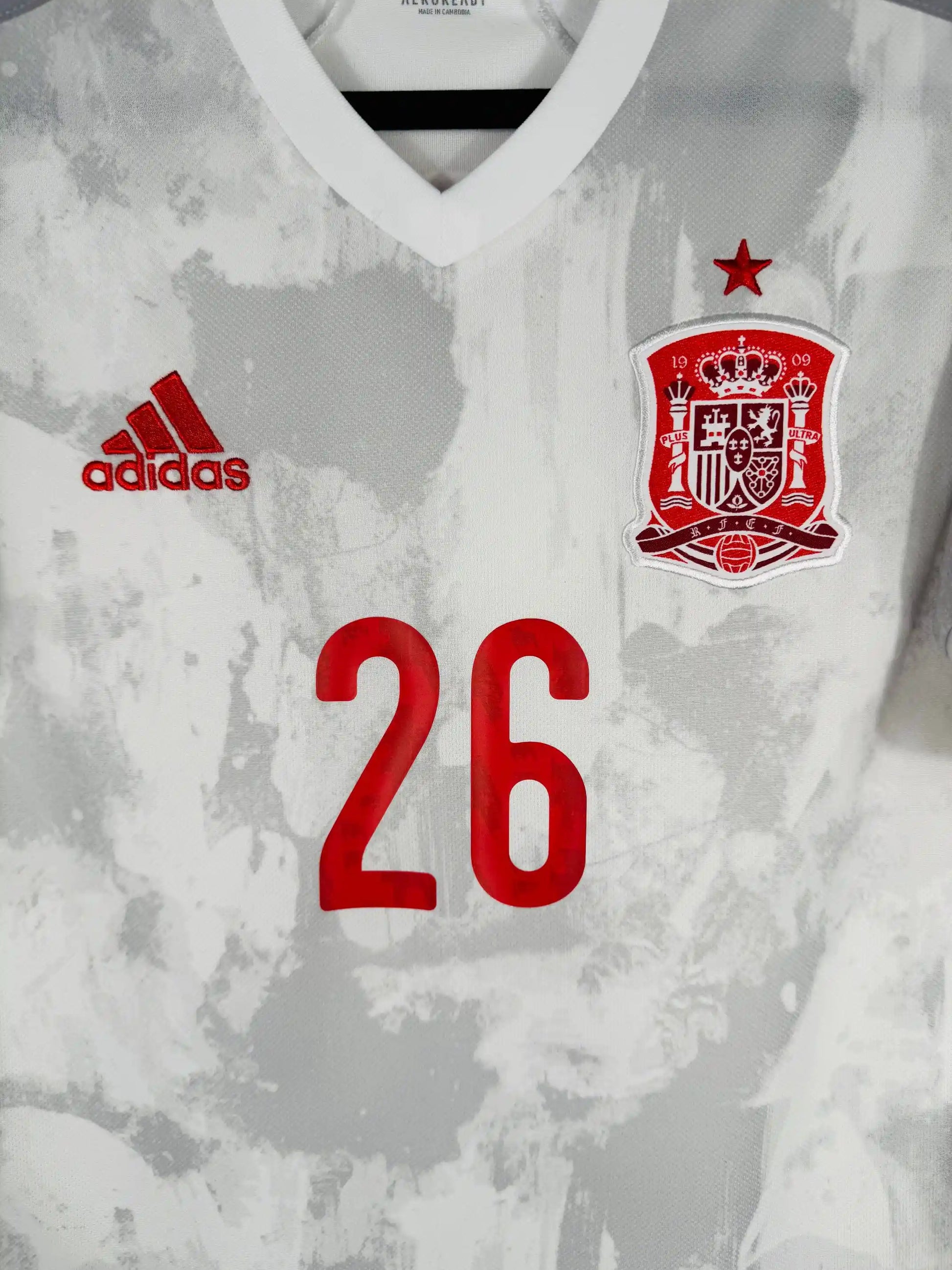 Détail écusson Real Federación Española de Fútbol couronne royale et motif filigrane gris architectural sur maillot Espagne extérieur Euro 2020