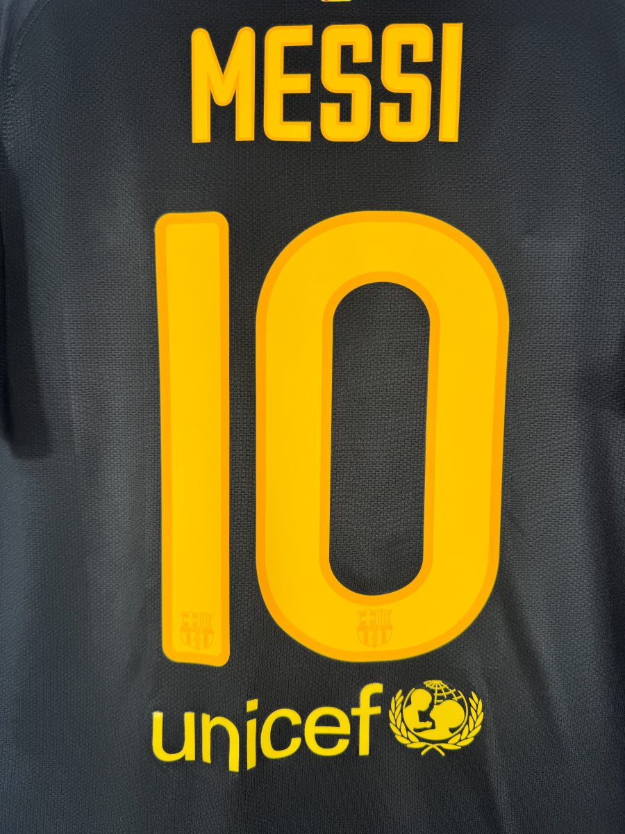 Détail du flocage jaune MESSI N°10 sur le maillot extérieur noir du FC Barcelone 2011-2012