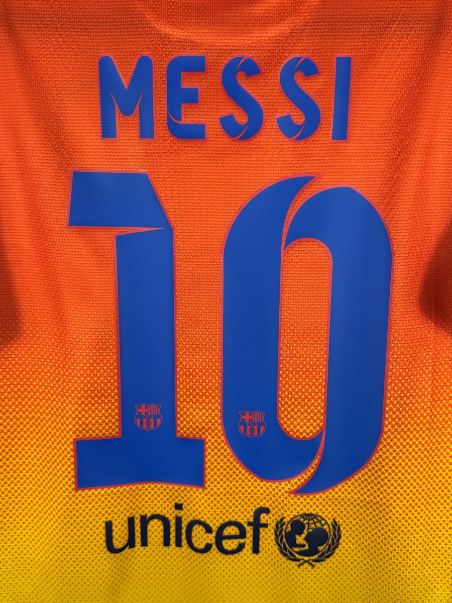 Détail du flocage bleu Messi 10 avec écussons FCB dans les chiffres, maillot FC Barcelone 2012-2013