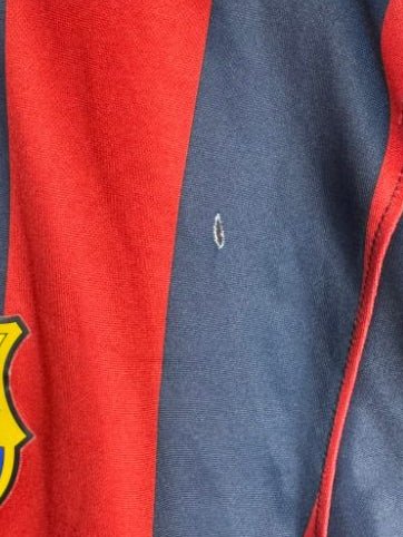 Gros plan sur le petit trou présent sur le maillot du FC Barcelone 2013-2014