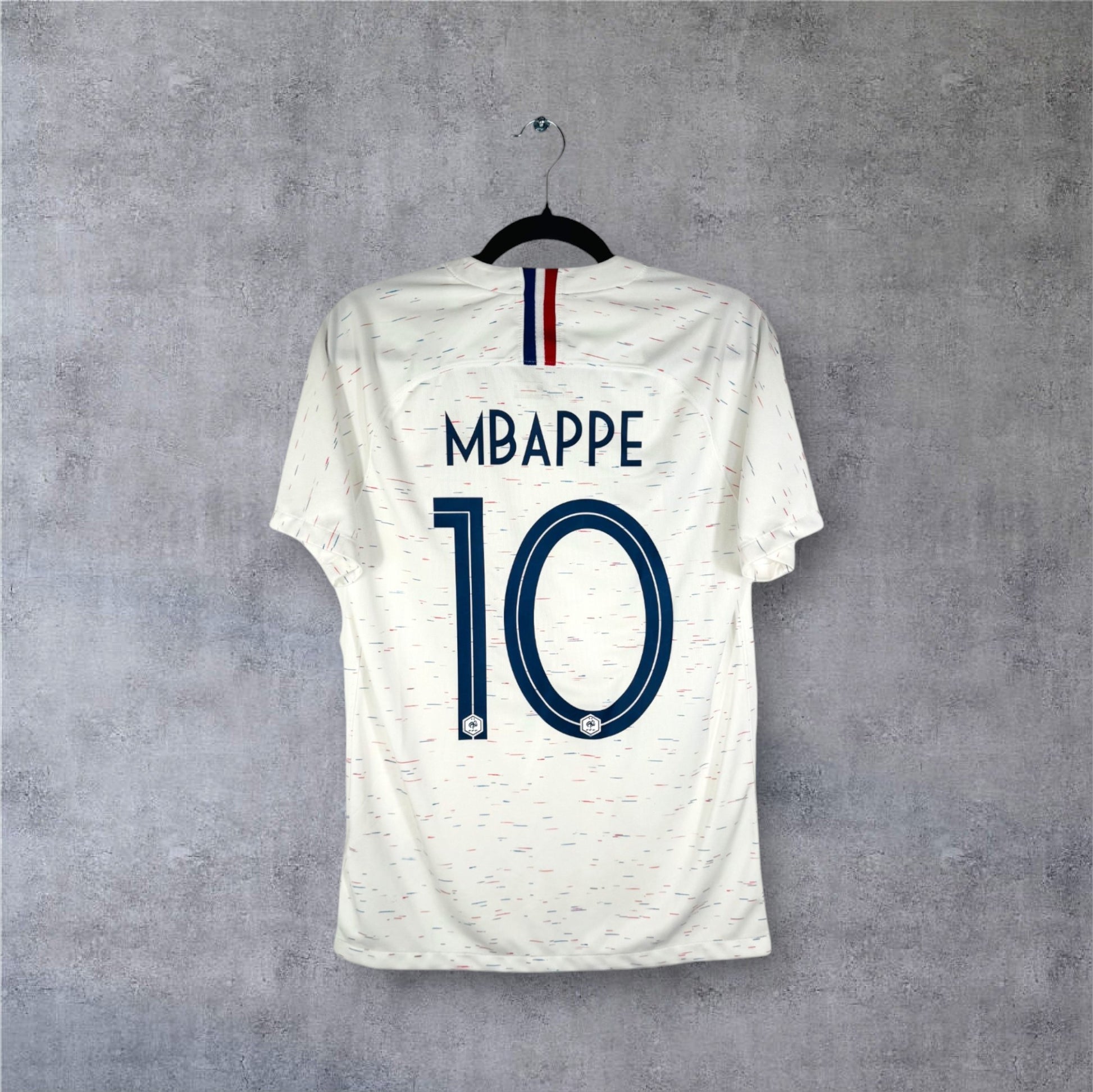 Flocage officiel bleu MBAPPE numéro 10 et détail tricolore au col sur maillot France blanc.