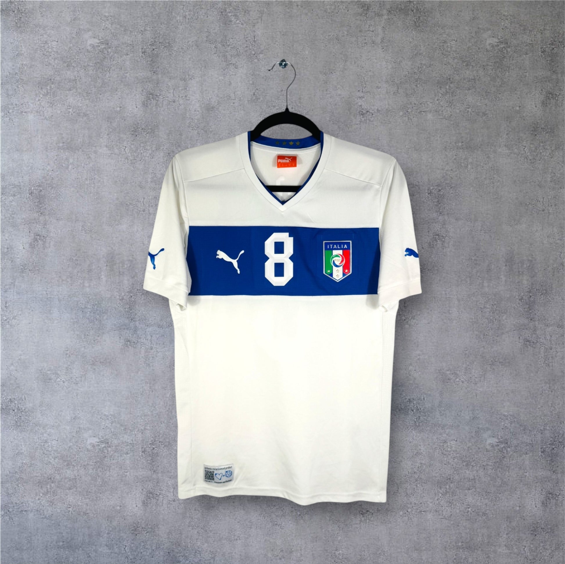 Vue de face du maillot Italie extérieur 2012 blanc avec bande horizontale bleue sur la poitrine.
