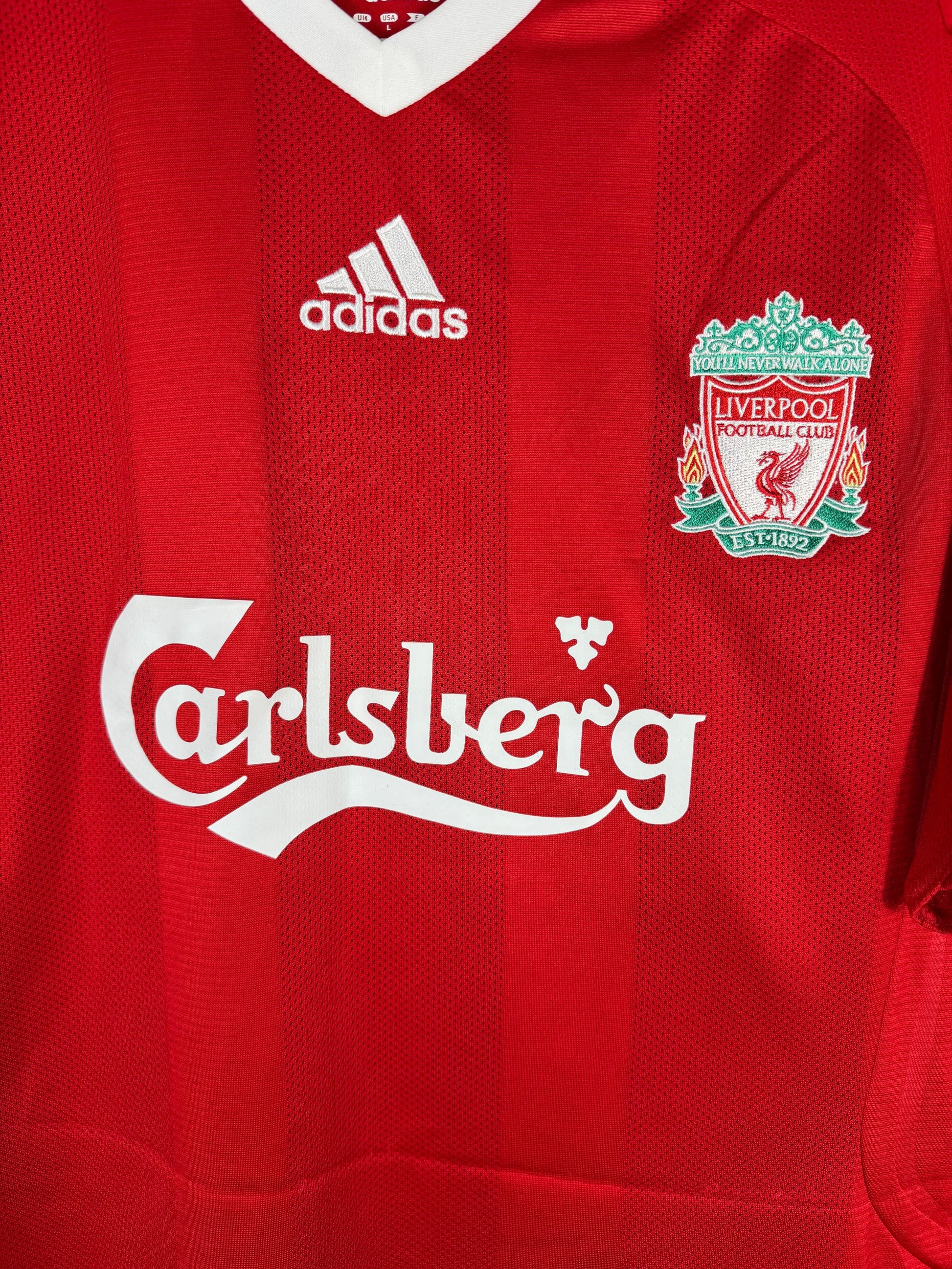 Détail écusson Liverbird Liverpool, logo Adidas et sponsor Carlsberg sur maillot domicile 2008-2010