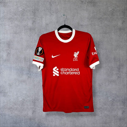 Maillot Liverpool 2023-2024 domicile de face, rouge à col et poignets blancs, sponsor Standard Chartered