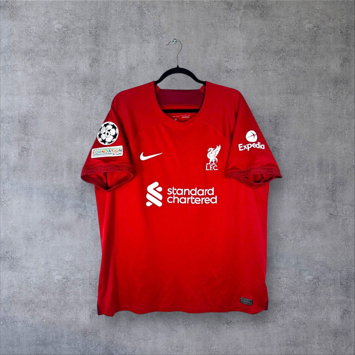 Vue de face du maillot Liverpool Domicile 2022/23 rouge uni avec logo Nike et sponsor standard chartered.
