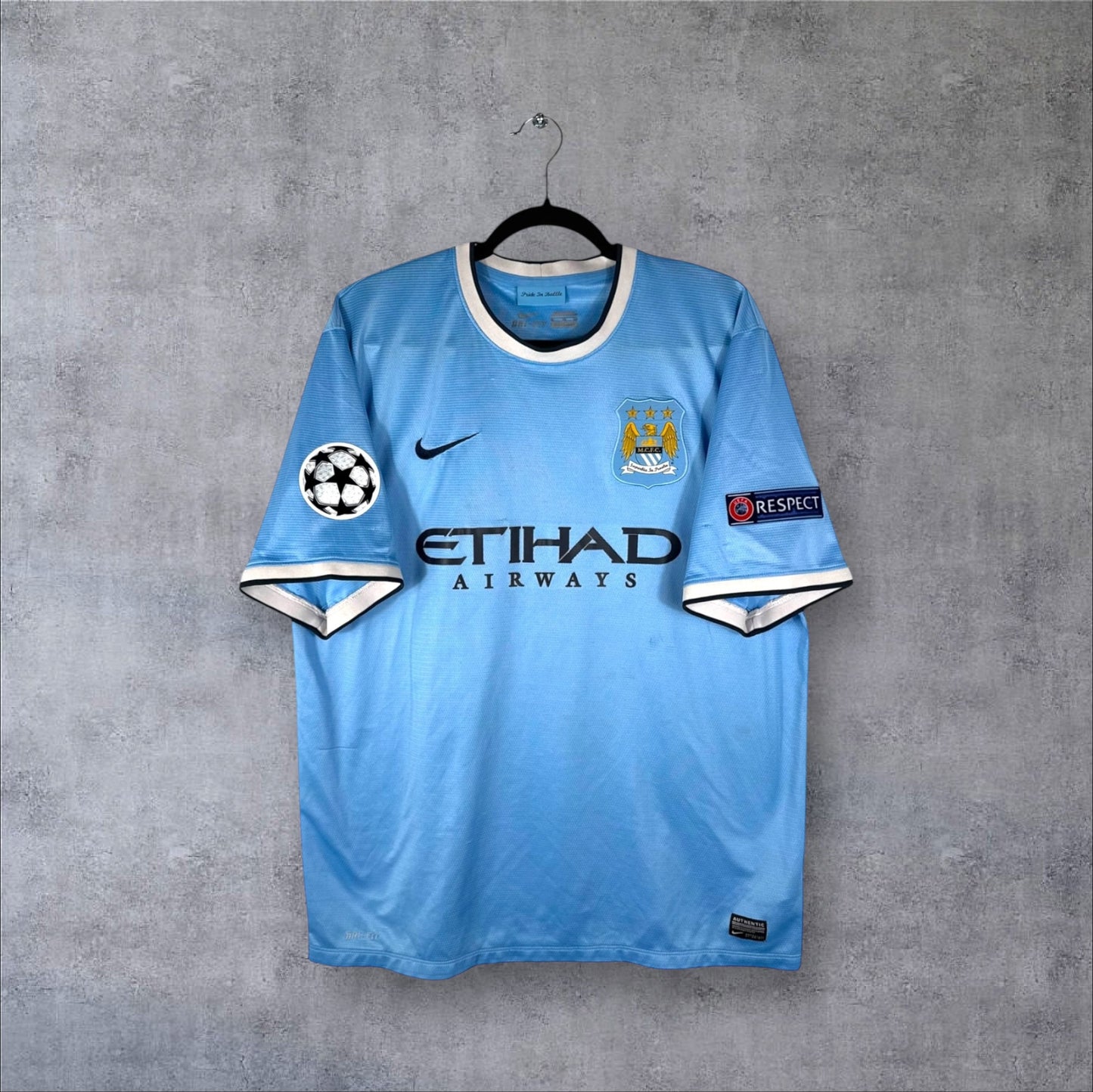 Vue de face du maillot Manchester City Domicile 2013/14 bleu ciel avec sponsor Etihad Airways et logo Nike.