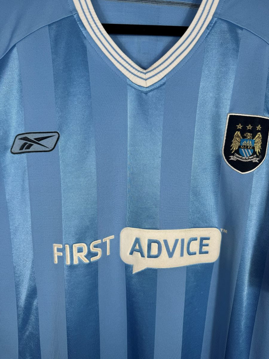 Écusson Manchester City brodé sur fond marine avec aigle doré, logo Reebok et sponsor First Advice, maillot domicile 2003-2004