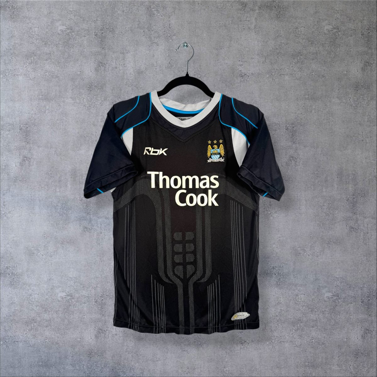 Maillot Manchester City 2006-2007 extérieur noir de face, motif ton sur ton, sponsor Thomas Cook, liserés bleu ciel