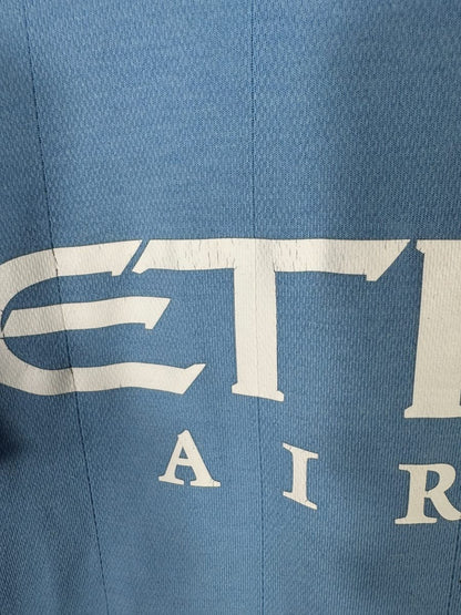 Craquelures fines sur les lettres E et T du sponsor Etihad, maillot Manchester City 2010-2011