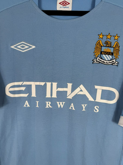 Écusson brodé Manchester City trois étoiles, losange Umbro et sponsor Etihad, maillot domicile 2010-2011