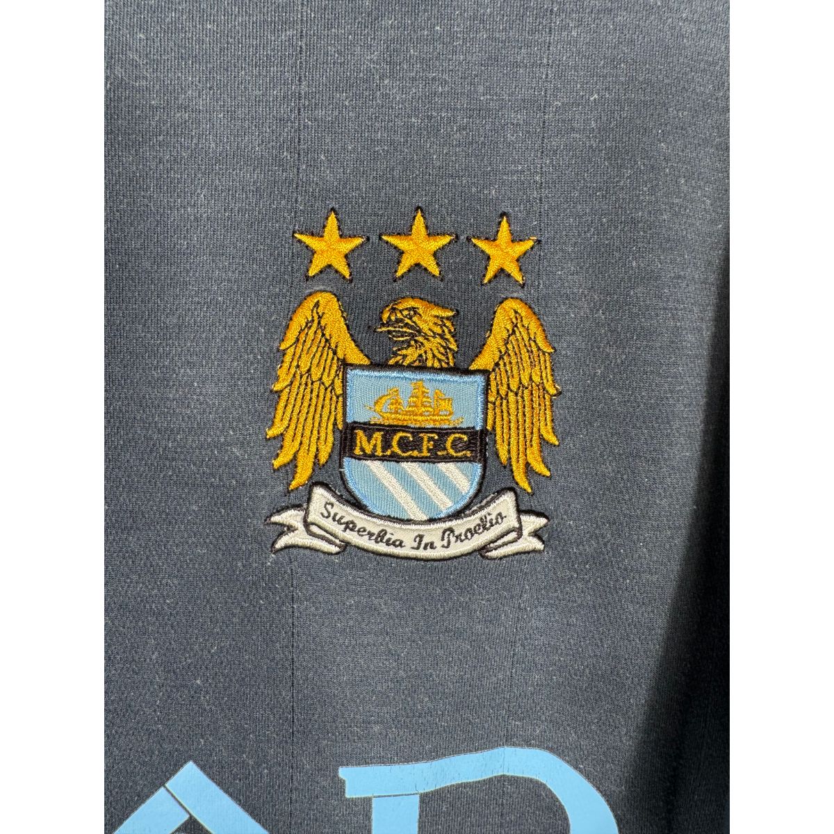 Détail de l'écusson de Manchester City et du logo Umbro