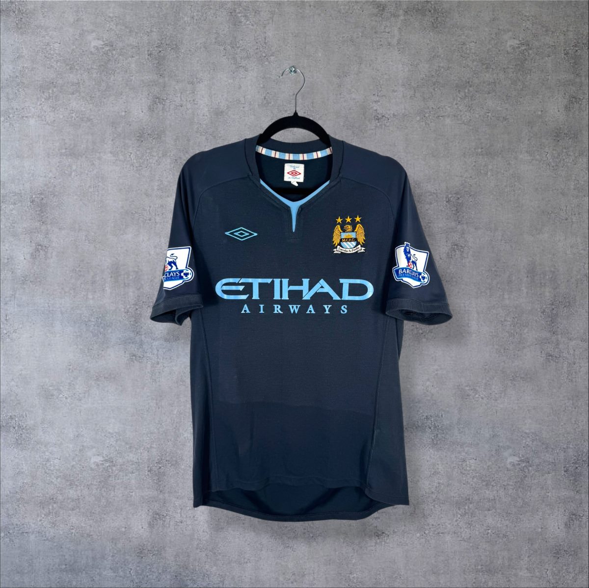 Maillot Manchester City 2010-2011 extérieur bleu nuit de face, sponsor Etihad bleu ciel, col bleu ciel