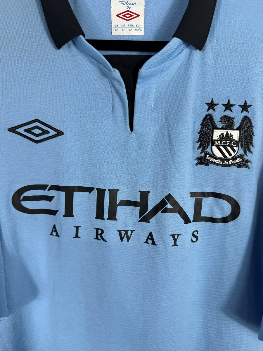 Écusson brodé Manchester City aux trois étoiles, col Tailored by Umbro et sponsor Etihad, maillot domicile 2012-2013