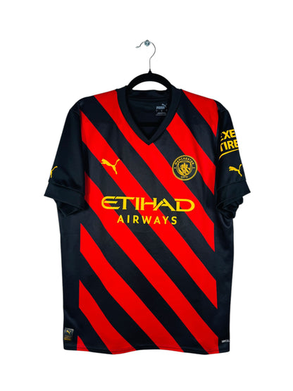 Maillot Manchester City 2022-2023 Extérieur Puma - Vue avant, taille L, couleur noir et rouge.