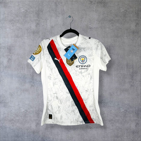 Maillot Manchester City KidSuper de face, écharpe rouge et noire en diagonale, sponsor Etihad et étiquettes attachées