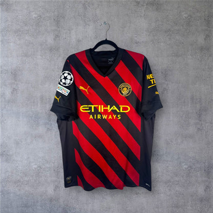Vue de face du maillot Manchester City Extérieur 2023 à rayures diagonales.