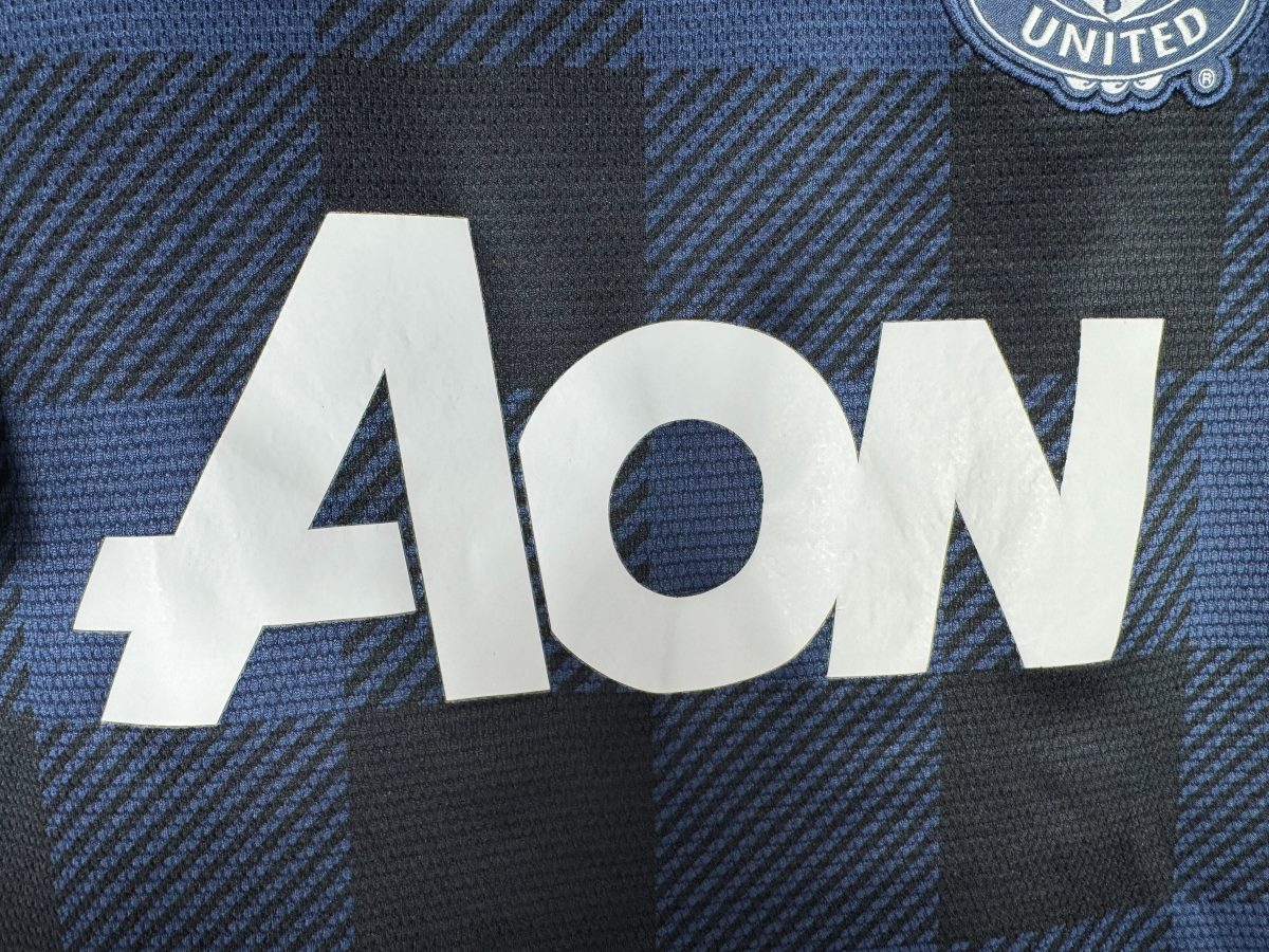 Détail du sponsor AON floqué en blanc sur le maillot Manchester United 2013-2014 extérieur, dernière saison du sponsor