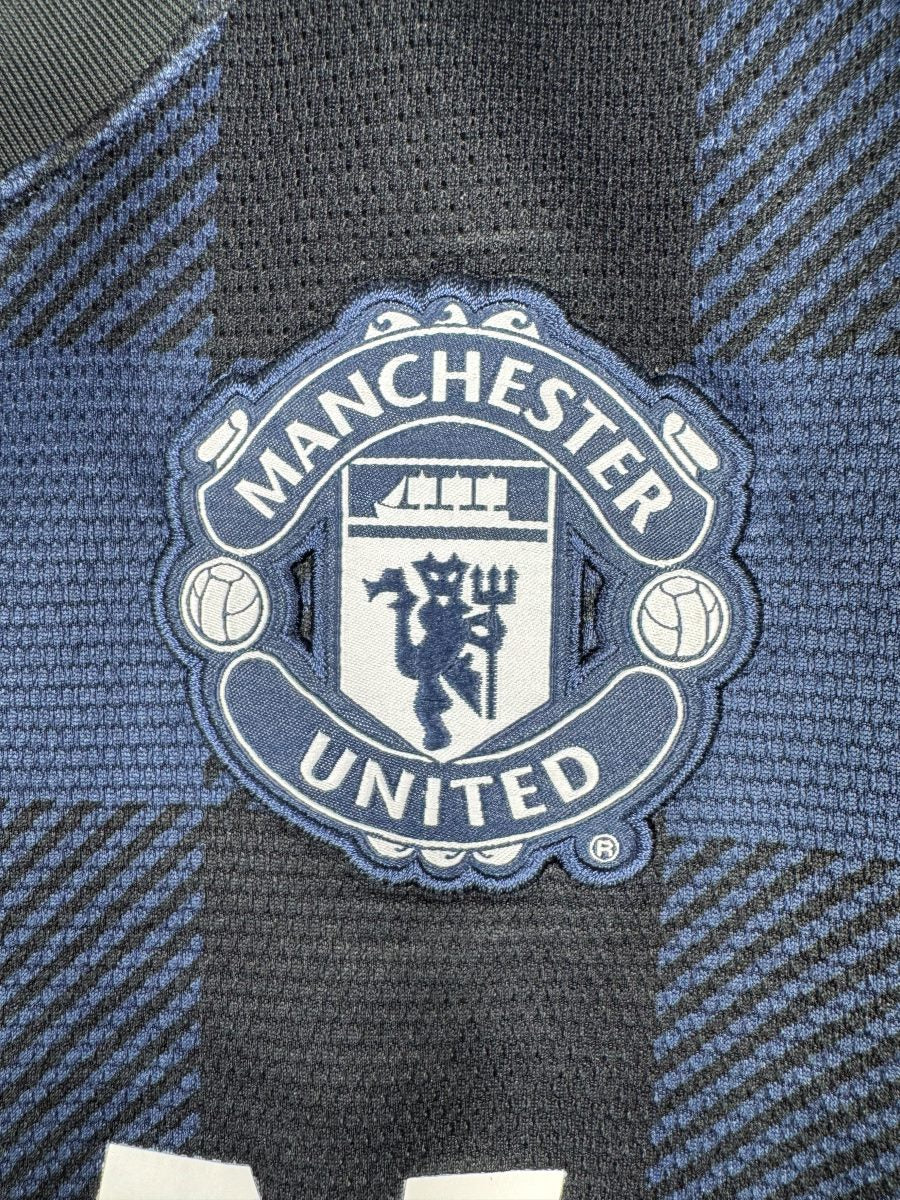 Écusson brodé Manchester United ton sur ton bleu marine sur le maillot extérieur 2013-2014, détail du diable rouge et du navire