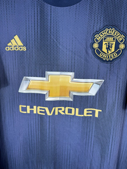 Détail de l'écusson doré brodé de Manchester United et du logo Chevrolet sur le maillot third 2018-2019