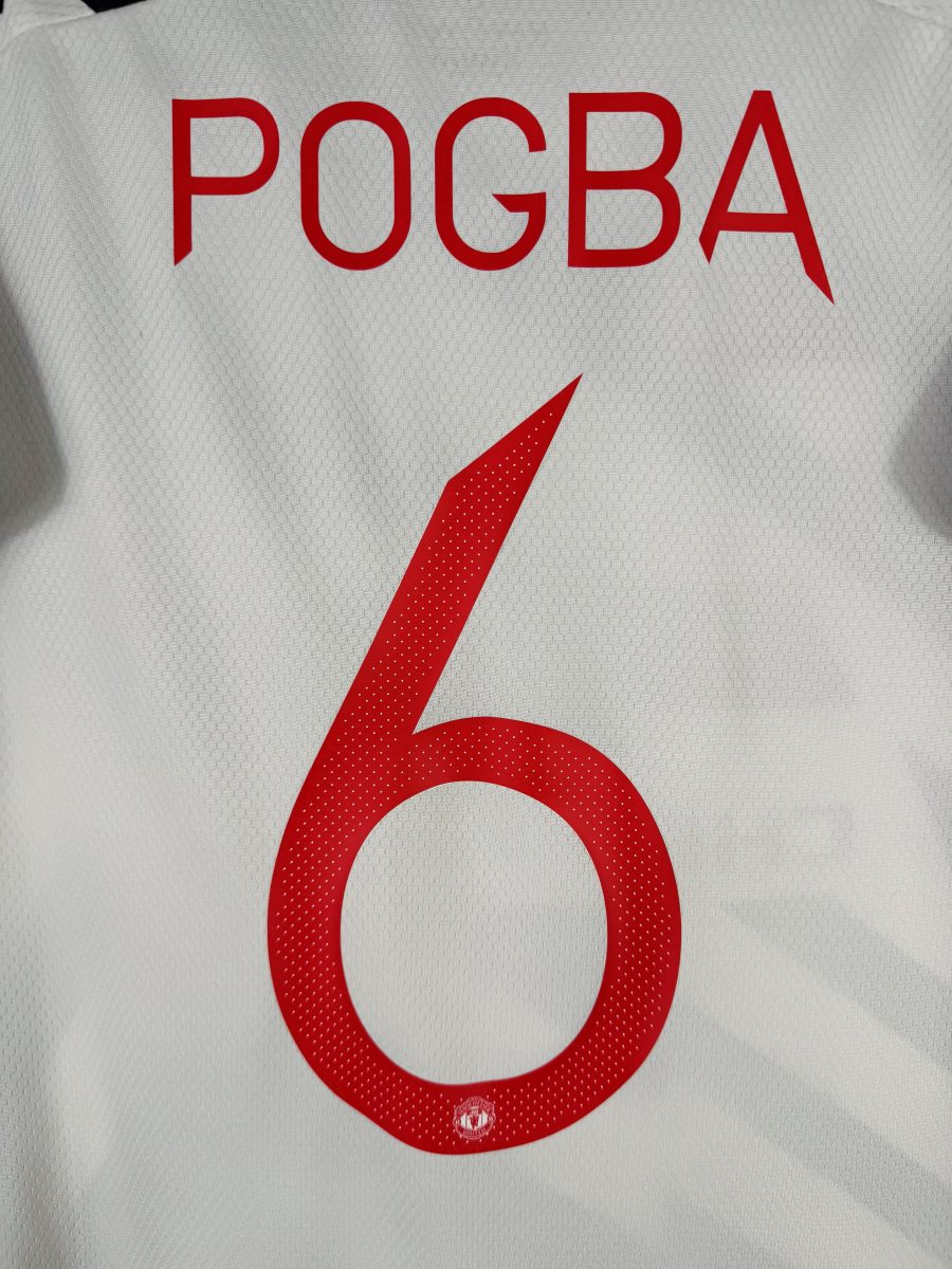 Détail du flocage Pogba N°6 rouge perforé avec écusson intégré, maillot Manchester United 2020-2021