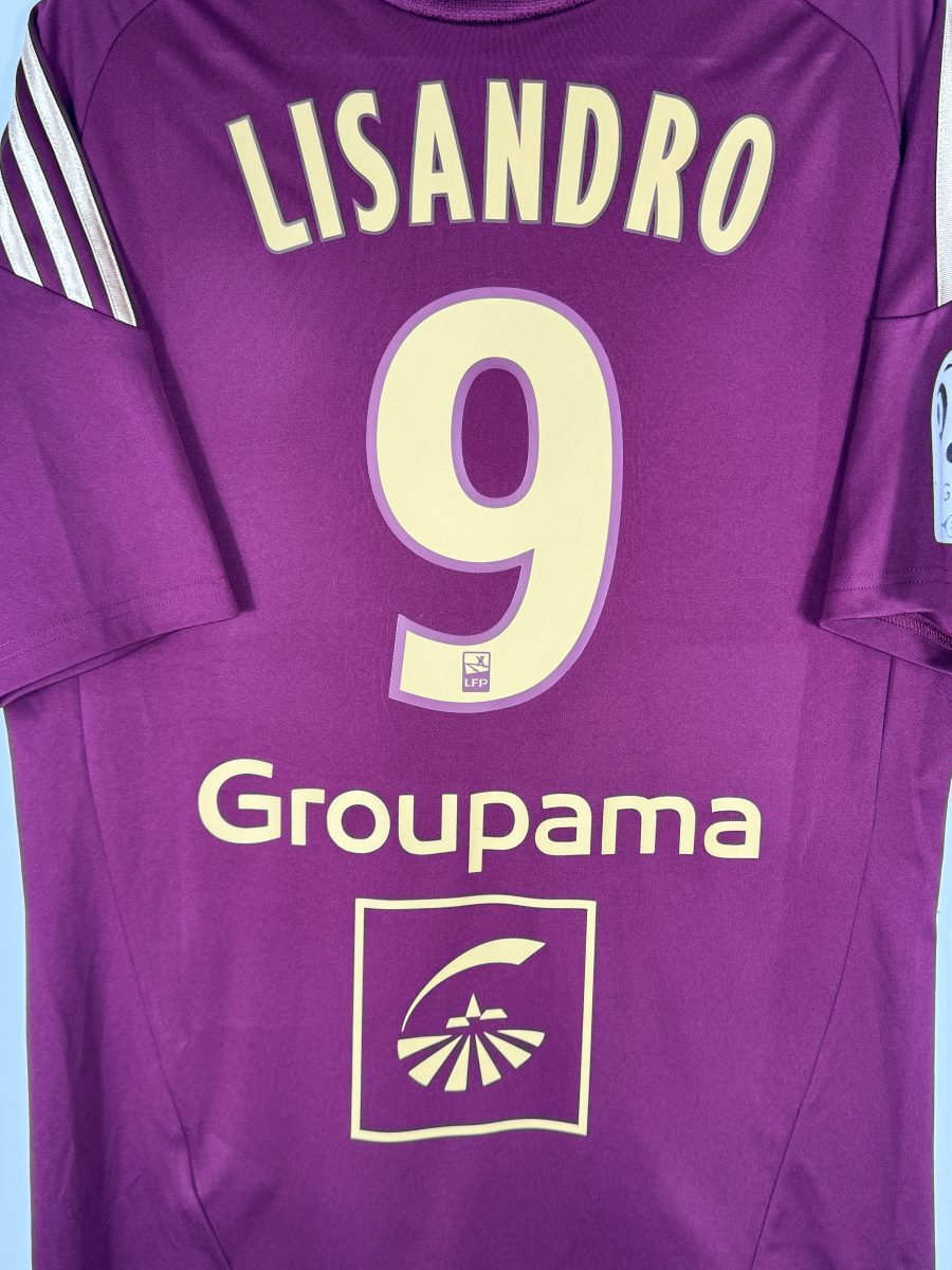 Détail du flocage LISANDRO numéro 9 avec logo LFP et sponsor Groupama, maillot OL 2010-2011