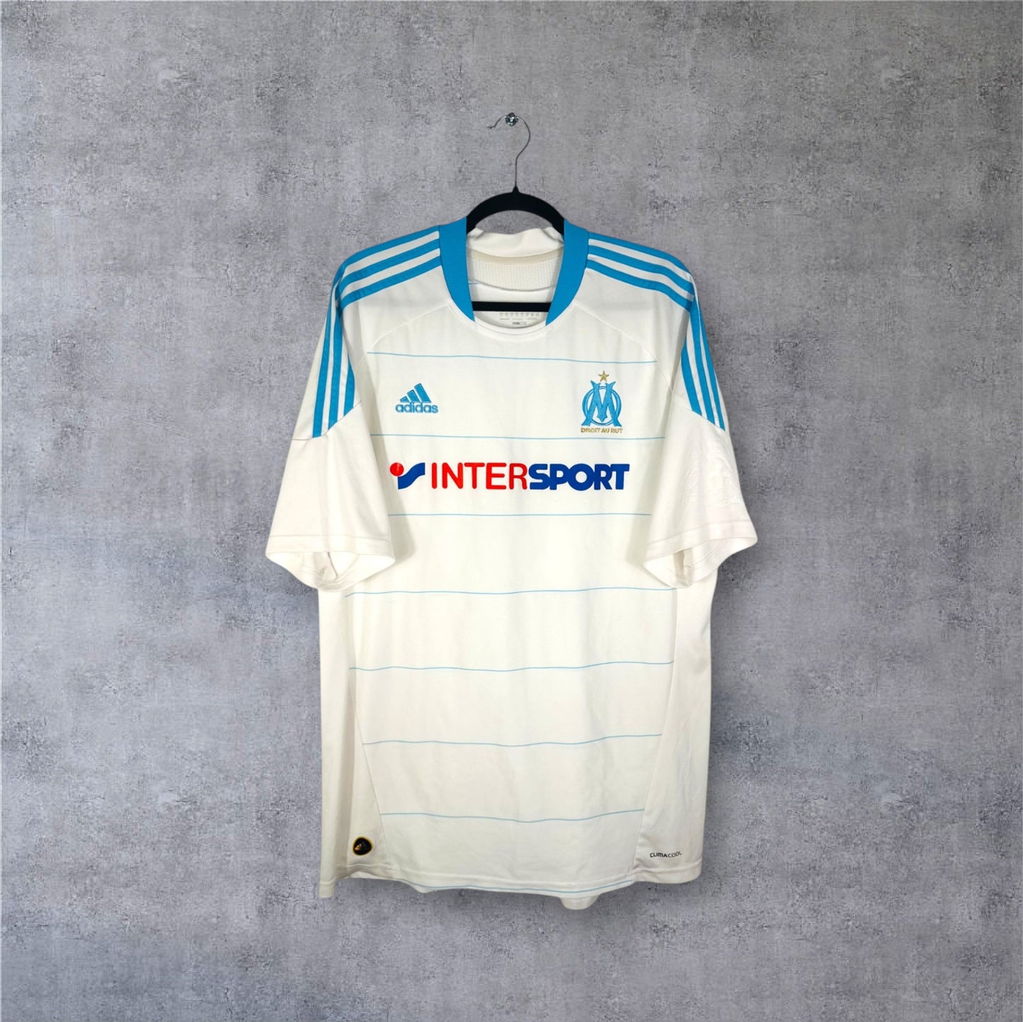 Vue de face du maillot blanc OM saison 2010/11 avec bandes bleues et dorées.