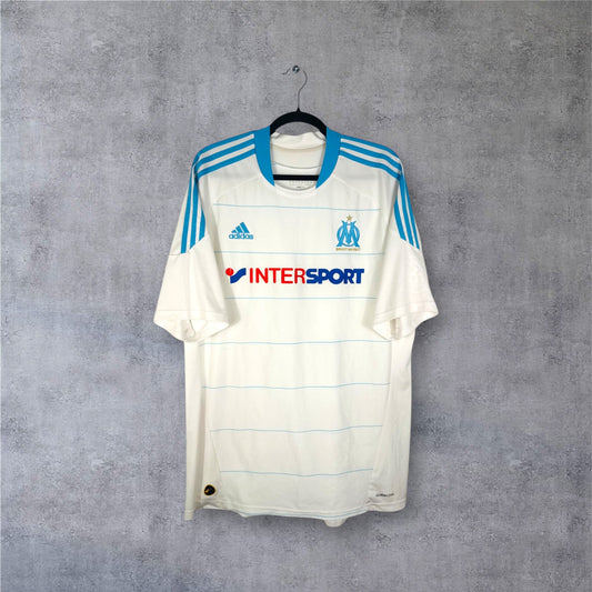 Vue de face du maillot blanc OM saison 2010/11 avec bandes bleues et dorées.