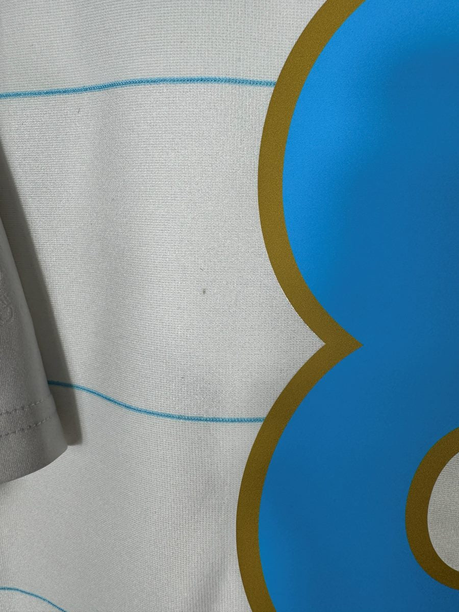 Gros plan du tissu blanc du maillot OM 2010-2011 montrant les micro-marques d'usage près du numéro